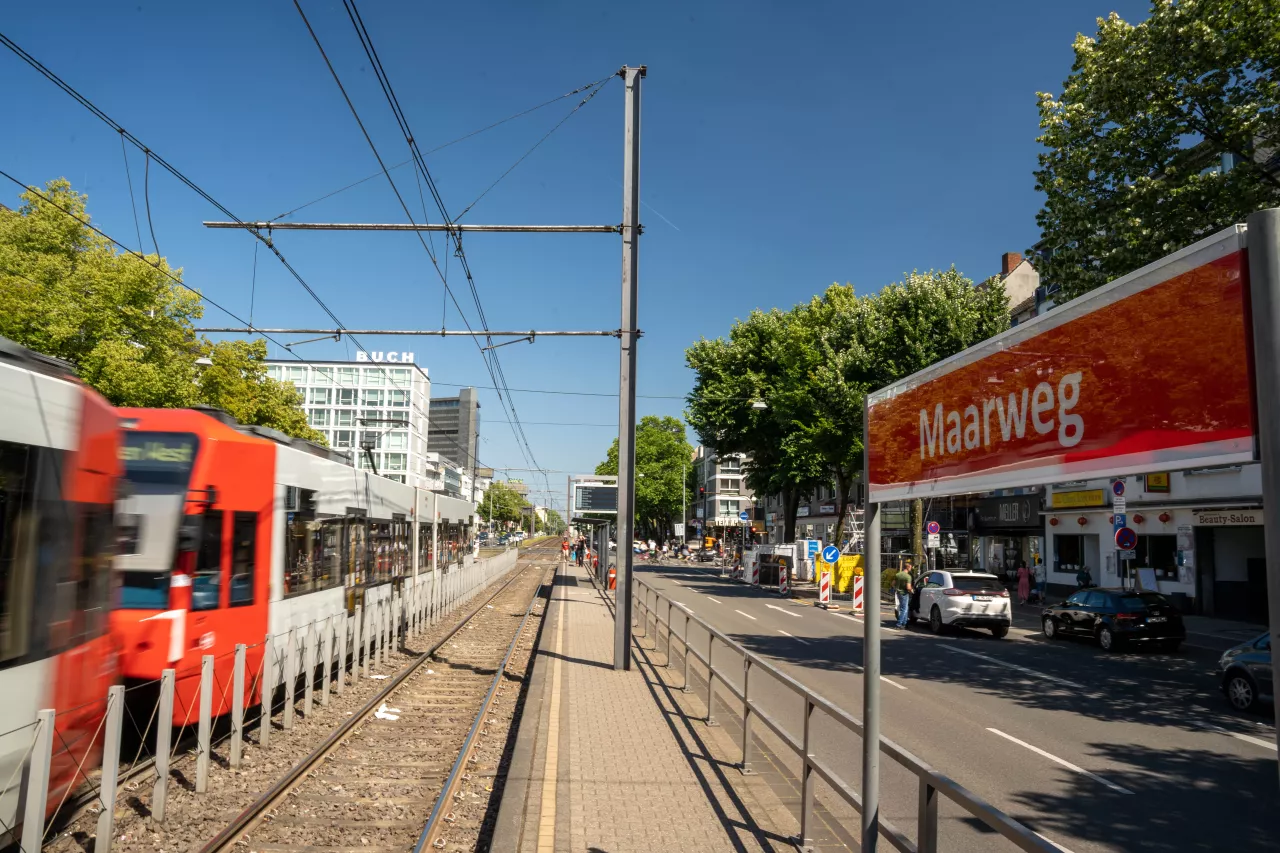 Haltestelle Maarweg Seitlicher Blick vom Bahnsteig auf das Haltestellenschild Maarweg mit Straßenbahn im Hintergrund